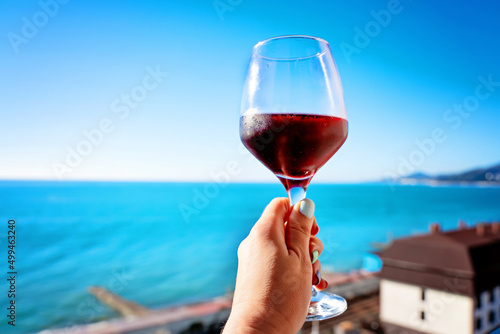 Photography a woman's hand holds a glass of red wine from the hotel window against the backg