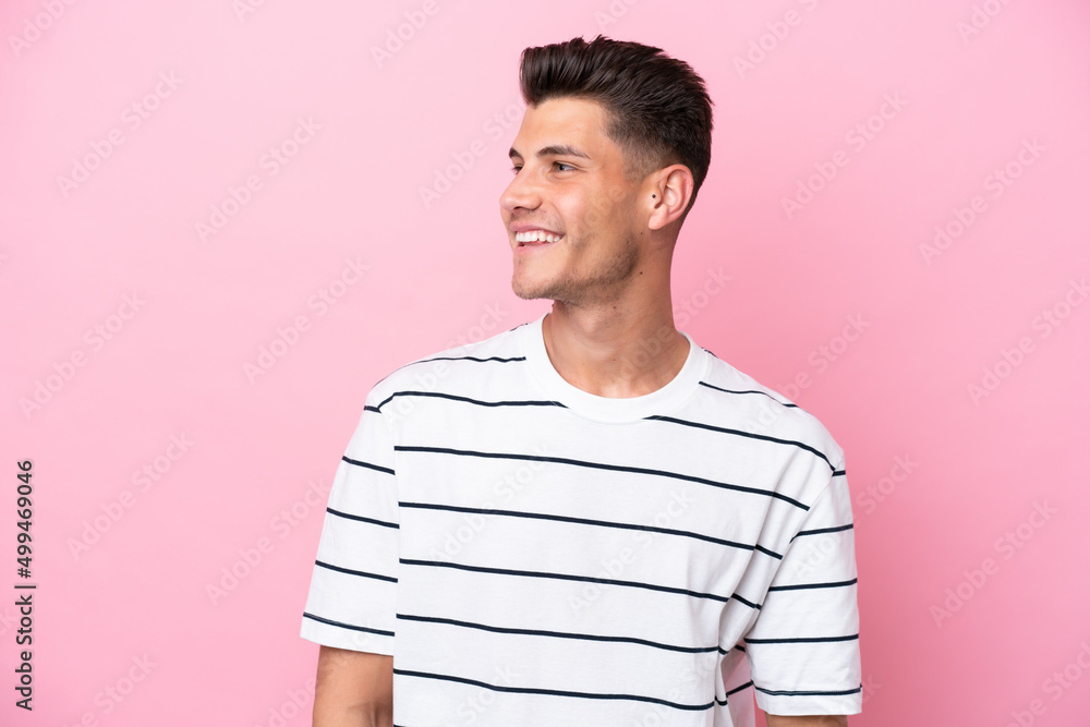 Young caucasian man isolated on pink background looking to the side and smiling Young caucasian man isolated on pink background looking to the side and smiling