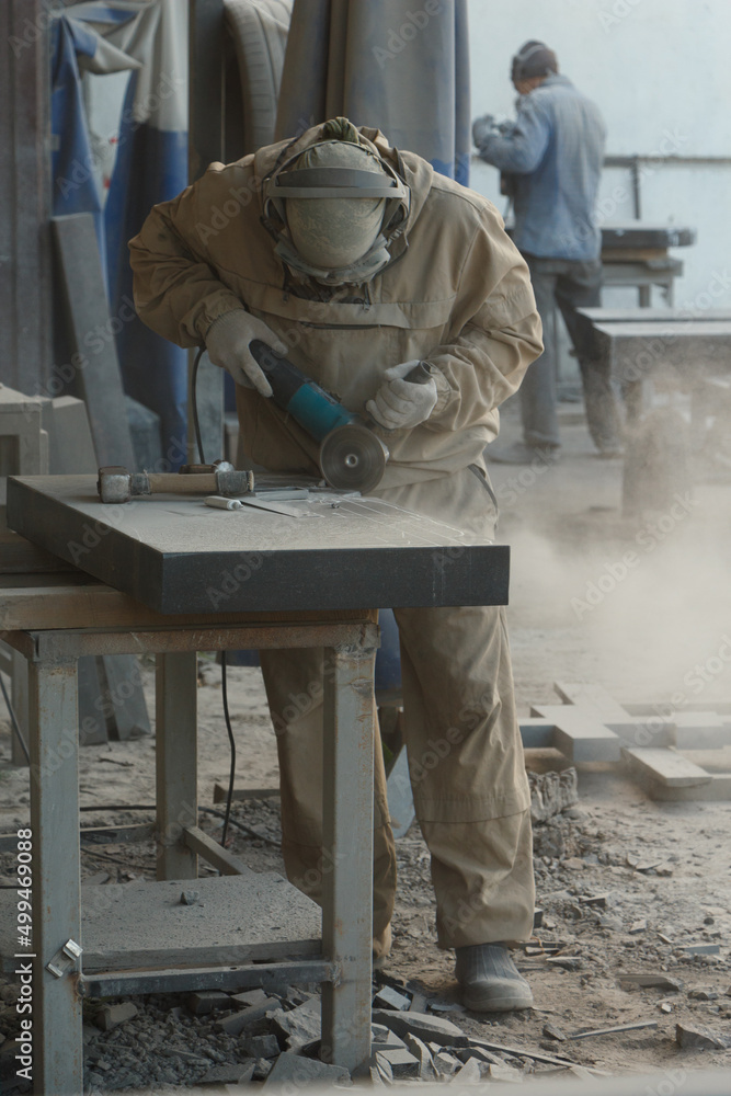Worker with a grinder in his hands is cutting granite, dust is flying. Worker with a grinder in his hands is cutting granite, dust is flying.