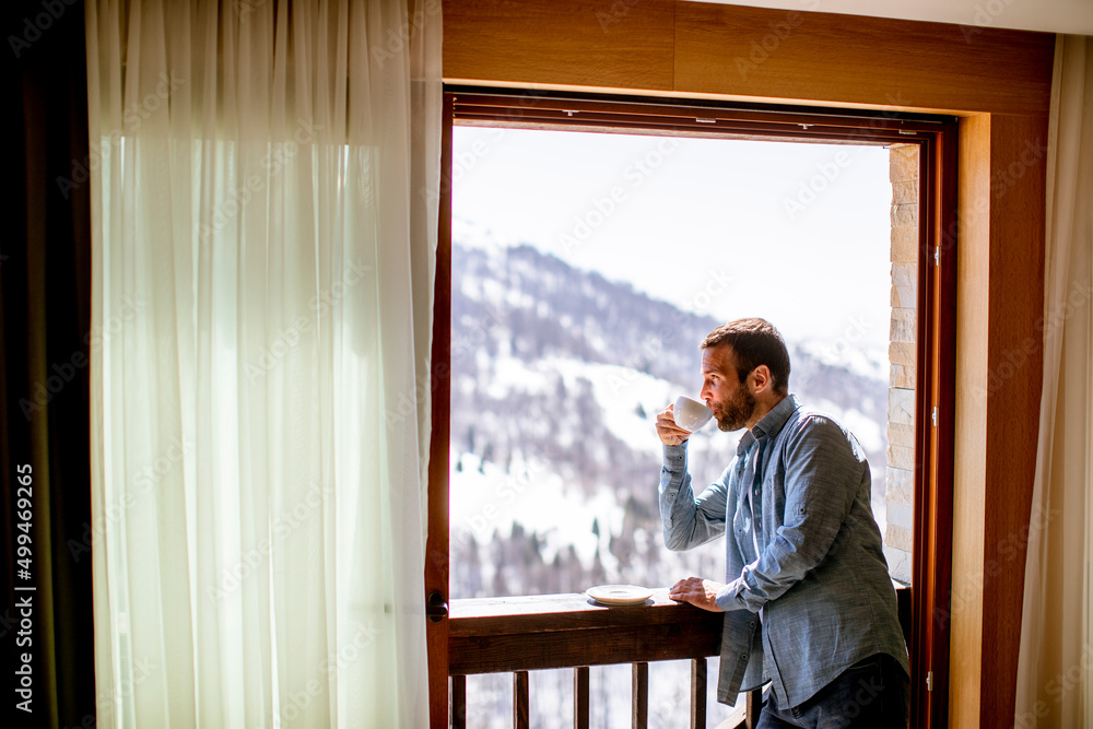Young man with cup of hot tea at winter window Young man with cup of hot tea at winter window