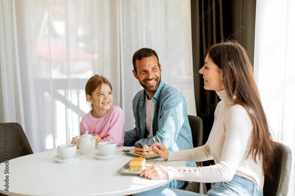 Happy young famila eat cakes and drink tea together Happy young famila eat cakes and drink tea together