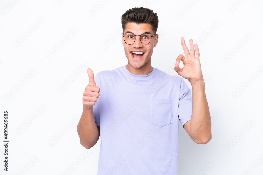 Young caucasian man isolated on white background showing ok sign and thumb up gesture Young caucasian man isolated on white background showing ok sign and thumb up gesture