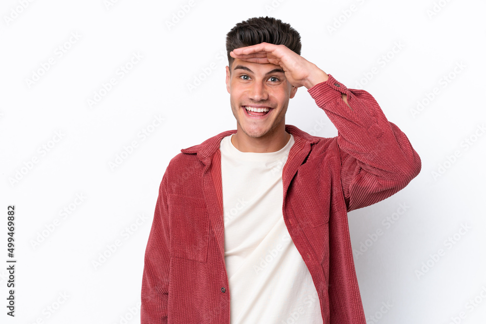 Young caucasian man isolated on white background looking far away with hand to look something Young caucasian man isolated on white background looking far away with hand to look something