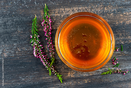 A saucer full of heather honey and a sprig of heather. photo