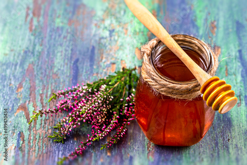 A saucer full of heather honey and a sprig of heather. photo