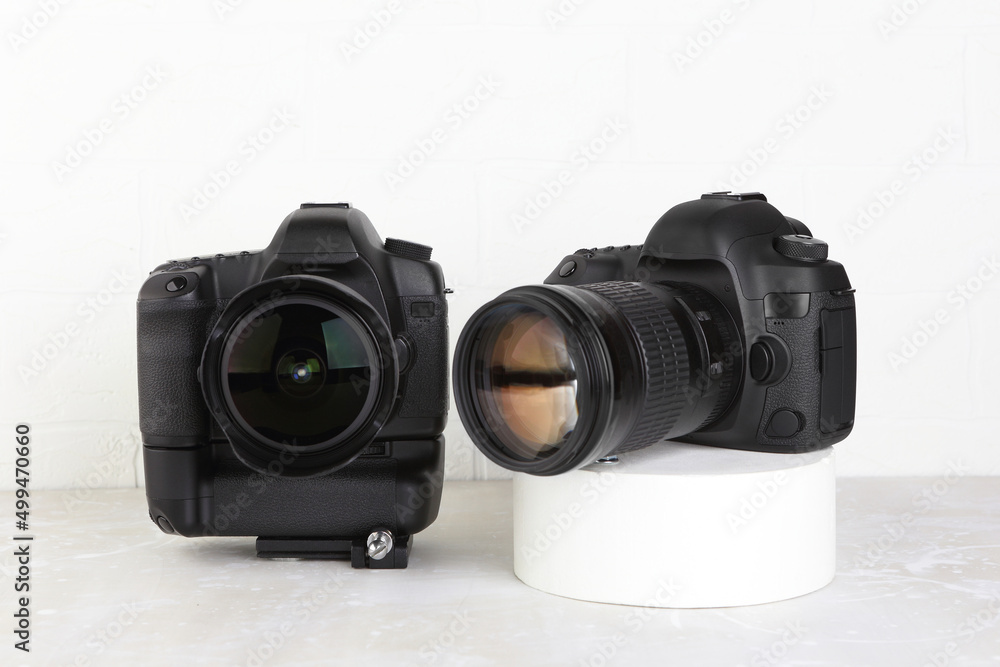 Fototapeta premium Two Big Black DSLR Digital Camera full frame sensor with lens on gray white cement background.