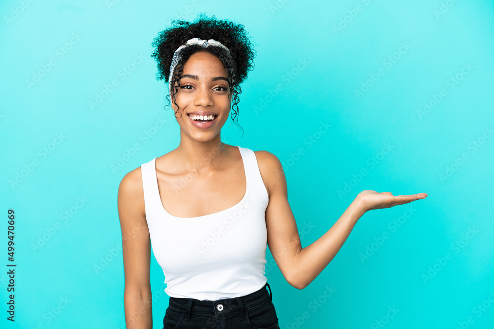 Young latin woman isolated on blue background holding copyspace imaginary on the palm to insert an ad Young latin woman isolated on blue background holding copyspace imaginary on the palm to insert an ad