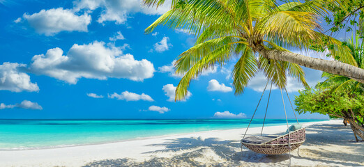 Tropical beach panorama as summer relax landscape with beach swing or hammock hang on palm tree over white sand sea beach banner. Amazing beach vacation summer holiday concept. Luxury romantic travel