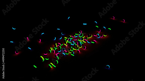 Fototapeta Naklejka Na Ścianę i Meble -  Colorful shining balls falling and rolling on a black background. Design. Many black children toy balls with neon lights falling on the floor.