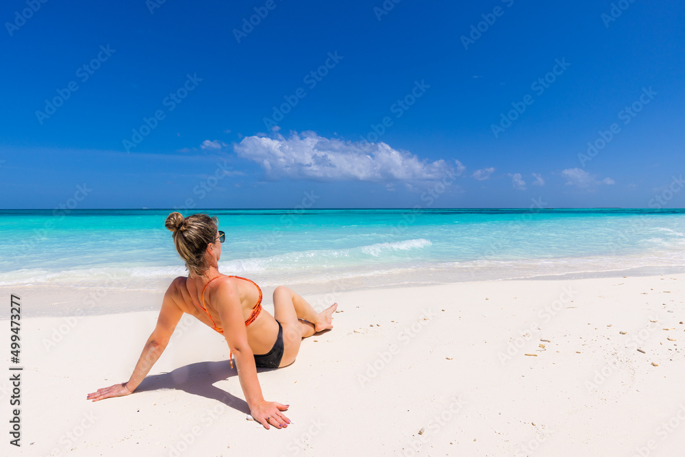 Young sexy woman relax on the beach. Perfect tropical island, beach shore, with turquoise ocean lagoon. Bikini, long legs, sunglasses enjoying summer vacation. Carefree woman beach portrait, leisure 