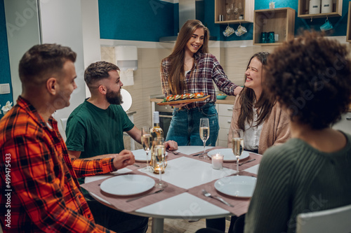 Group of friends enjoying dinner while sitting at the kitchen table together