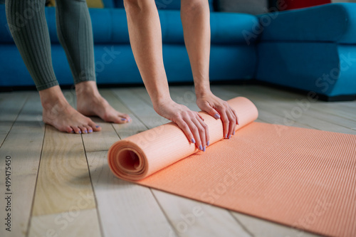 Woman folding pink exercise mat while practicing yoga at home