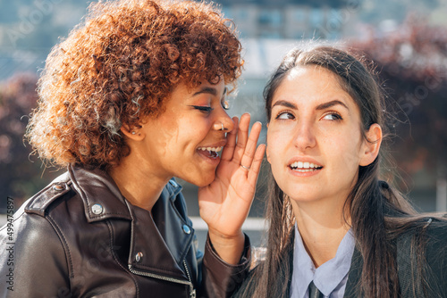 girl gossiping or whispering a secret in her friend's ear photo