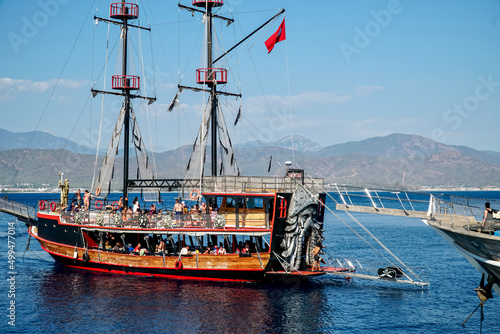 A tourist ship full of people sunbathing on deck and enjoying a guided tour of the Aegean Sea. The concept of the pirate ship