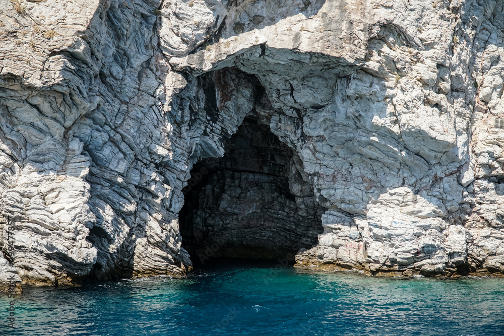 Cave. Entrance to the sea cave. Blue, clear water against the rocks backdrop Cave. Entrance to the sea cave. Blue, clear water against the rocks backdrop