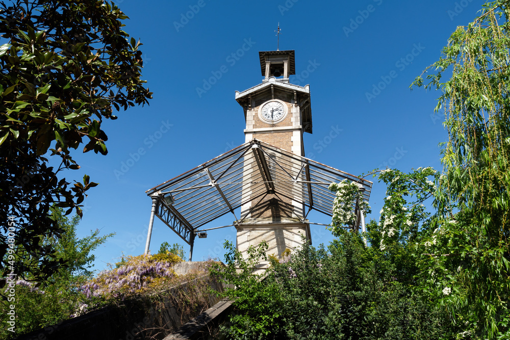 Old Clock Tower of Georges Brassens Public Park located in the 15th arrondissement of Paris, France. - obrazy, fototapety, plakaty 