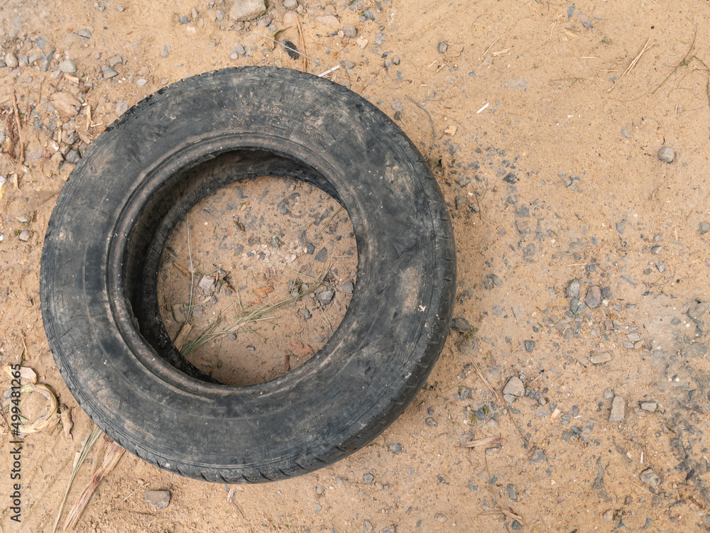 One black old car tire lies on the sandy ground. One black old car tire lies on the sandy ground.