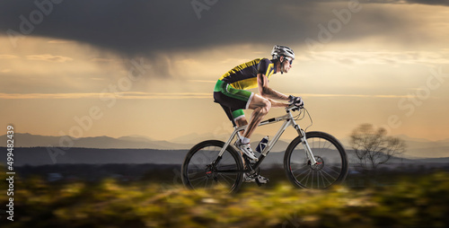 Fotografie, Obraz Mountain Bike cyclist riding single track at sunset
