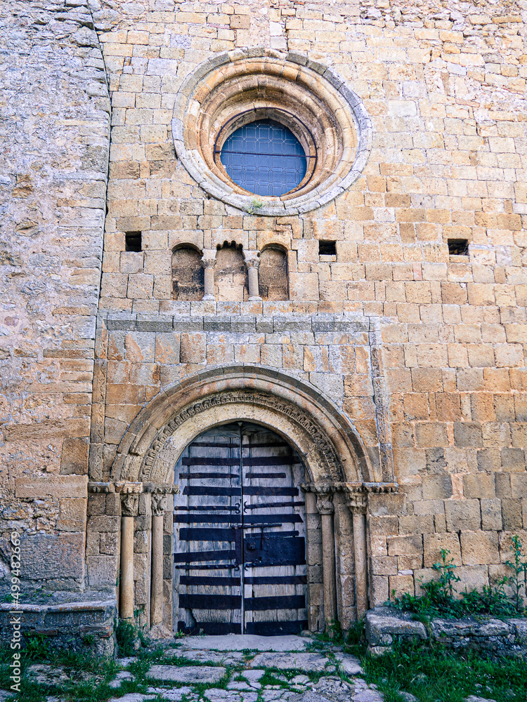 Fachada de piedra de una iglesia en Soria, España, con una puerta de madera, decorada con arcos y columnas antiguas, en verano de 2021