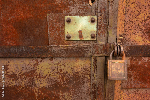 A large metal padlock on a rusty door.A forgotten room.Rusty metal wall. © Svetliy