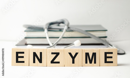 enzyme word written on wooden blocks and stethoscope on light white background