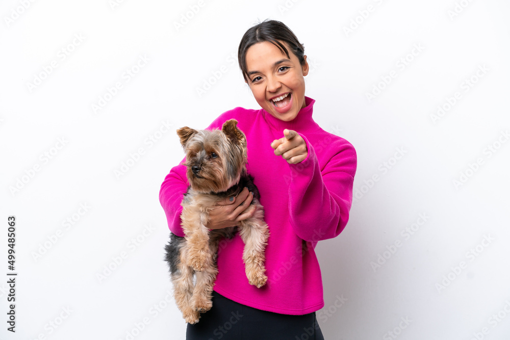 Young hispanic woman holding a dog isolated on white background points finger at you with a confident expression Young hispanic woman holding a dog isolated on white background points finger at you with a confident expression