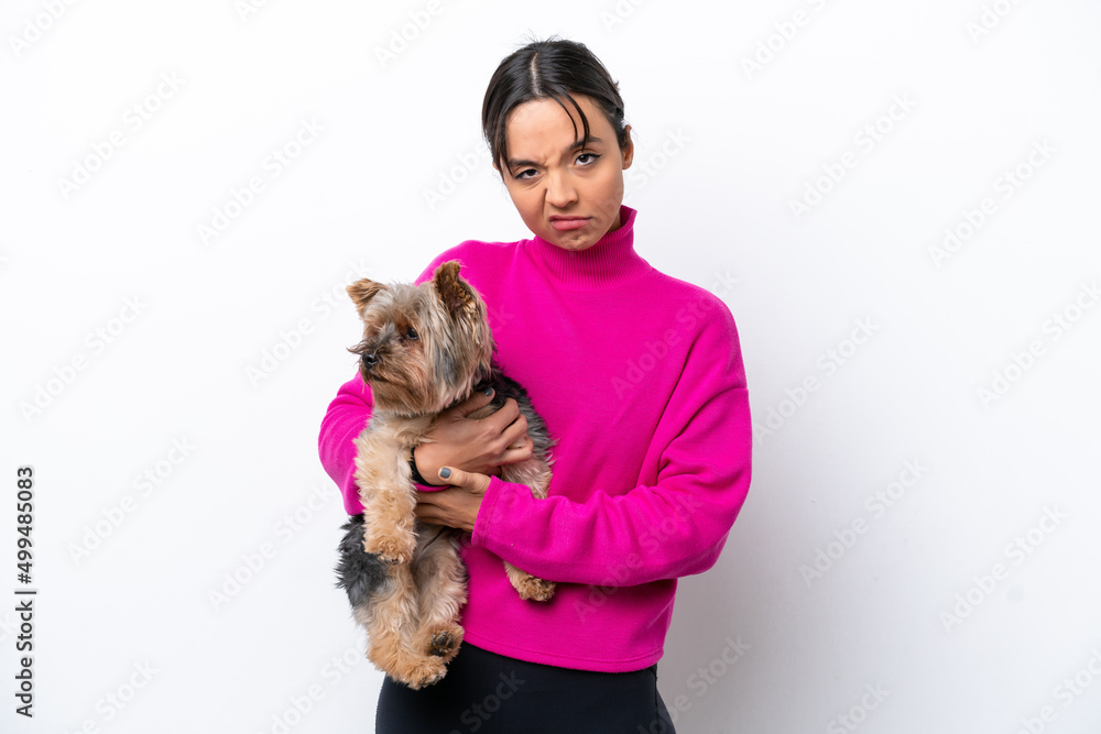 Young hispanic woman holding a dog isolated on white background with sad expression Young hispanic woman holding a dog isolated on white background with sad expression