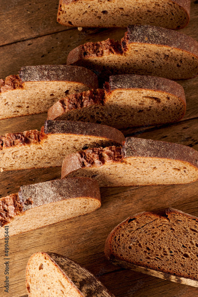 Bread, traditional homemade bread cut into slices on a rustic wooden background, close-up.