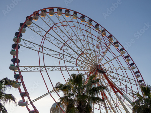 Ferris wheel against the sky. Amusement park by the sea. Rest zone. Round mechanism. Height lovers.