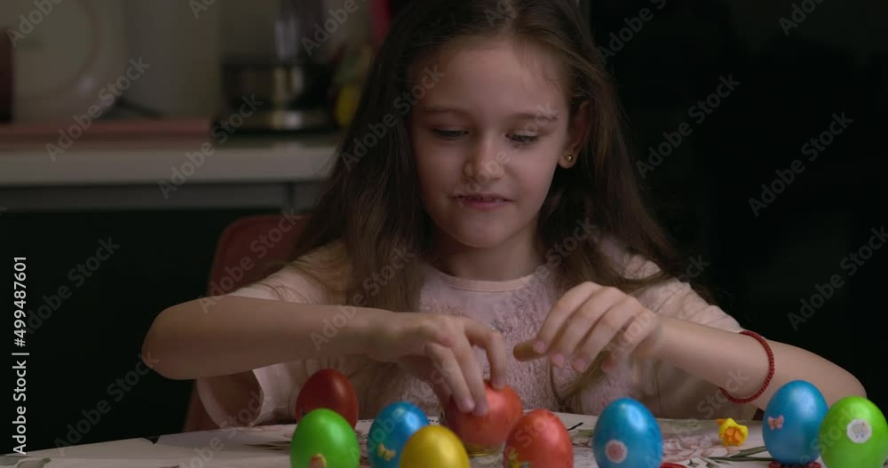 The girl glues decorative stickers on Easter eggs and folds them. Easter eggs, the feast of the passover. The girl glues decorative stickers on Easter eggs and folds them. Easter eggs, the feast of the passover.
