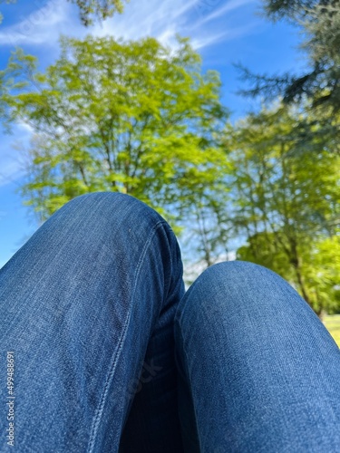 Legs and jeans, person sitting on nature .