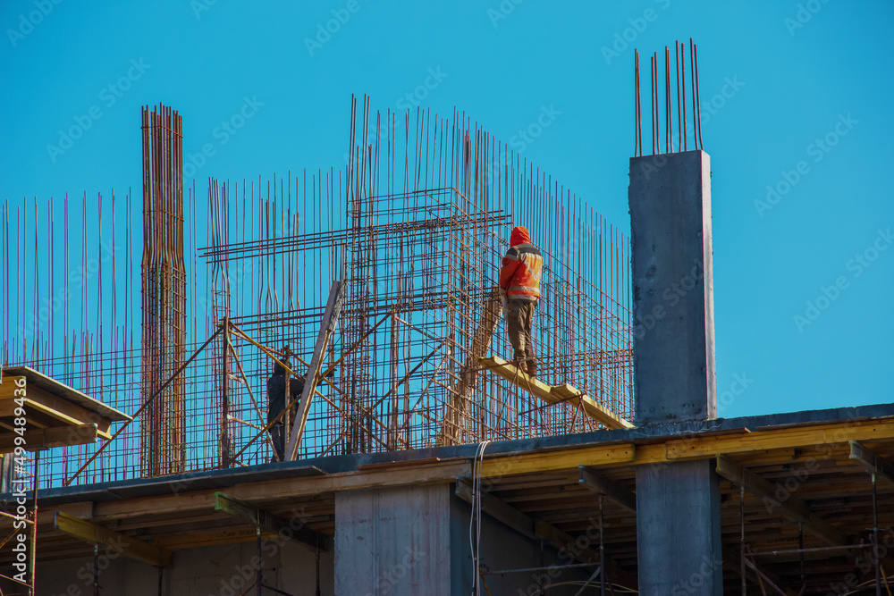 A worker prepares formwork for a modern metal-concrete structure of a residential building.