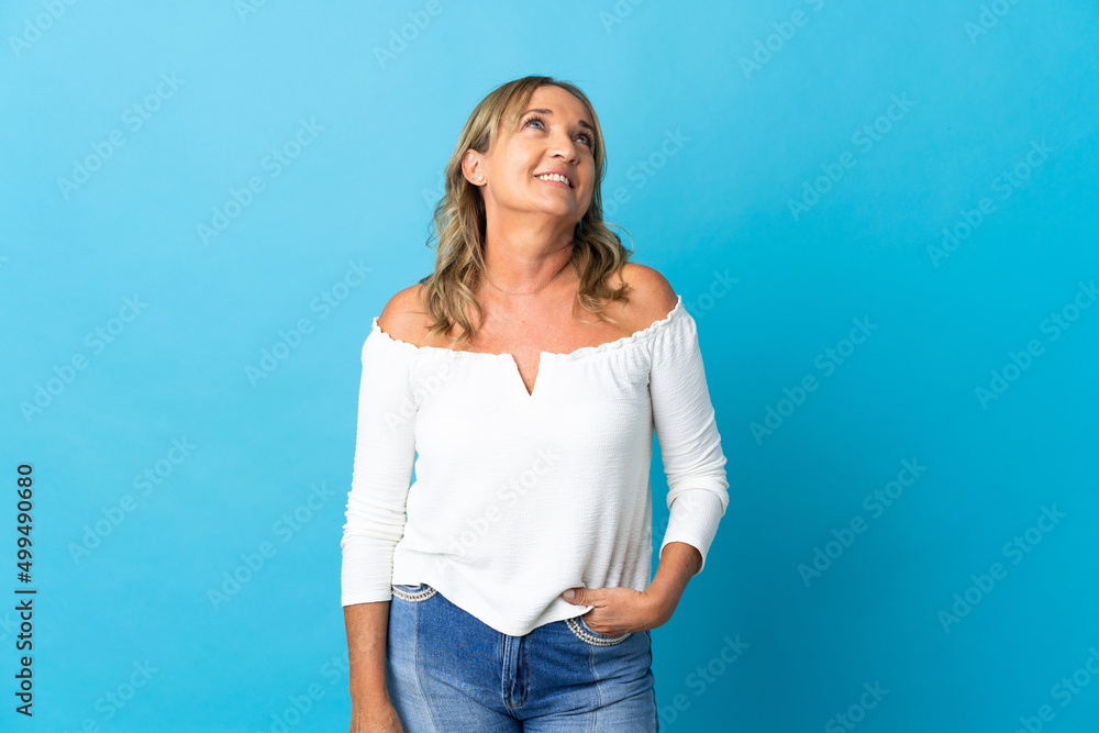 Middle aged blonde woman over isolated background thinking an idea while looking up Middle aged blonde woman over isolated background thinking an idea while looking up
