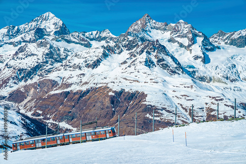 View of red train climbing to gornergrat station against mountain range photo