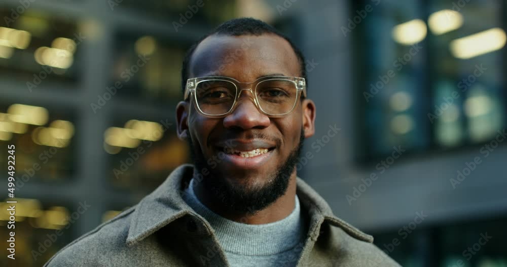 African-American man smiling looking at the camera near a modern building African-American man smiling looking at the camera near a modern building