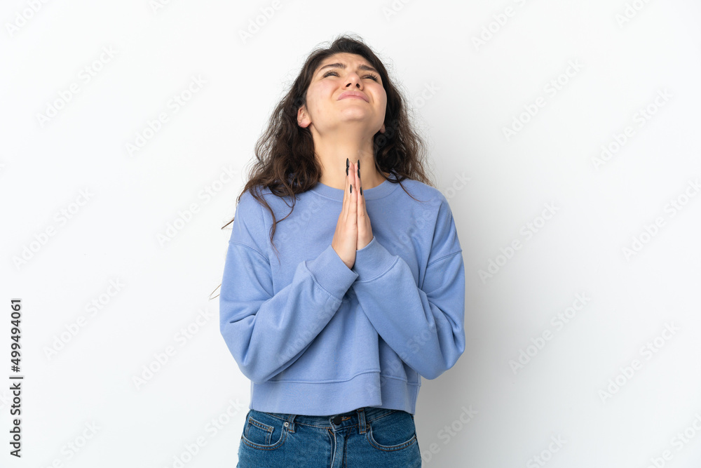 Teenager Russian girl isolated on white background keeps palm together. Person asks for something Teenager Russian girl isolated on white background keeps palm together. Person asks for something