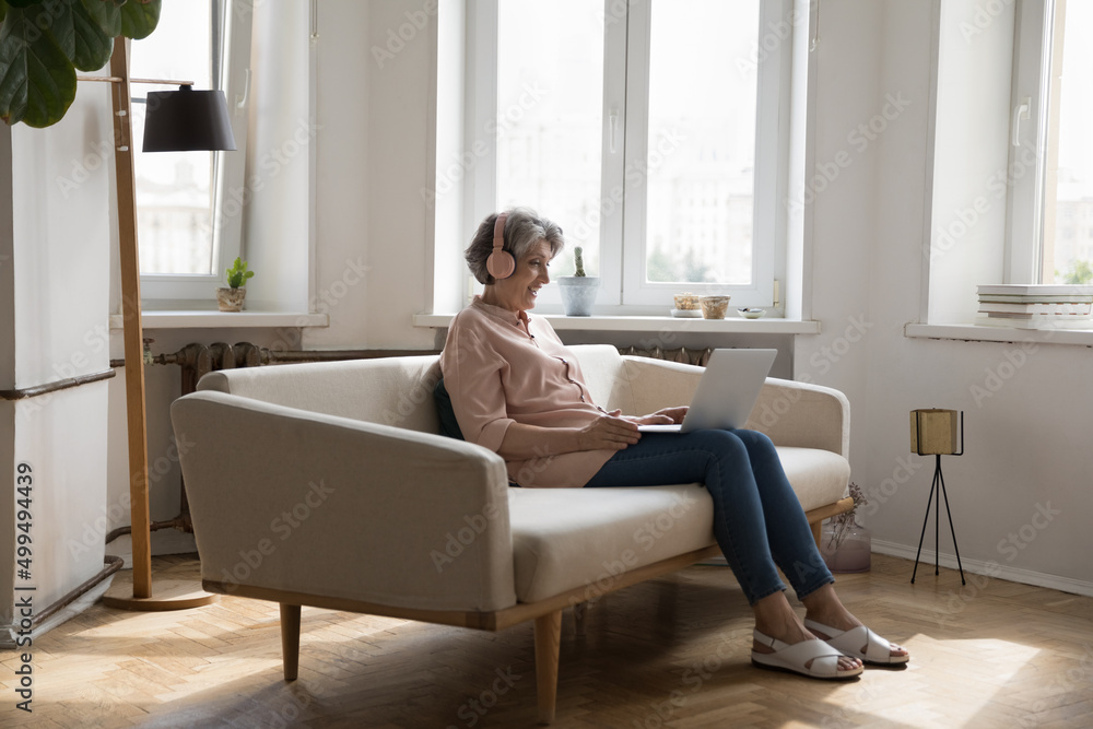 Older woman wear headphones staring at laptop make video call, communicate to friend or grown up children via video conference application smile enjoy talk. Medical online counselling event concept Older woman wear headphones staring at laptop make video call, communicate to friend or grown up children via video conference application smile enjoy talk. Medical online counselling event concept
