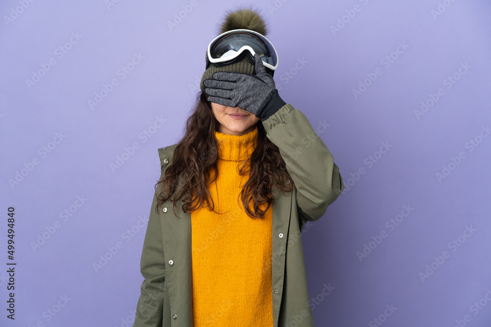 Teenager Russian girl with snowboarding glasses isolated on purple background covering eyes by hands. Do not want to see something
