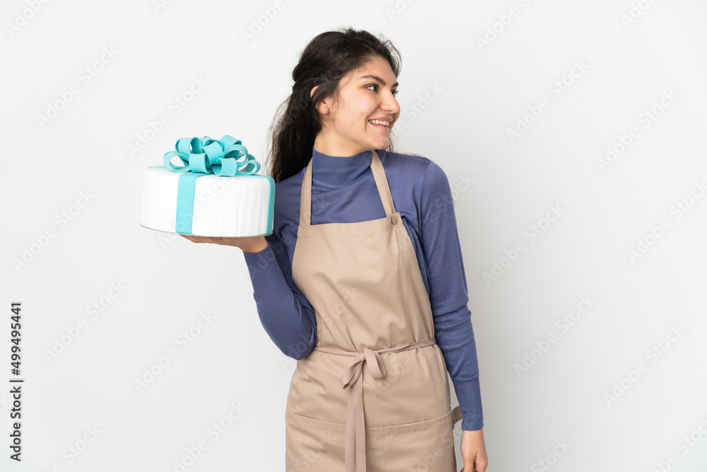 Pastry Russian chef holding a big cake isolated on white background looking side Pastry Russian chef holding a big cake isolated on white background looking side