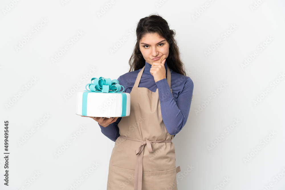 Pastry Russian chef holding a big cake isolated on white background thinking Pastry Russian chef holding a big cake isolated on white background thinking