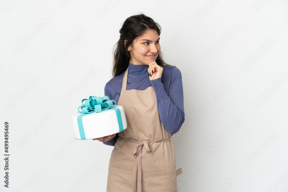 Pastry Russian chef holding a big cake isolated on white background looking to the side and smiling Pastry Russian chef holding a big cake isolated on white background looking to the side and smiling