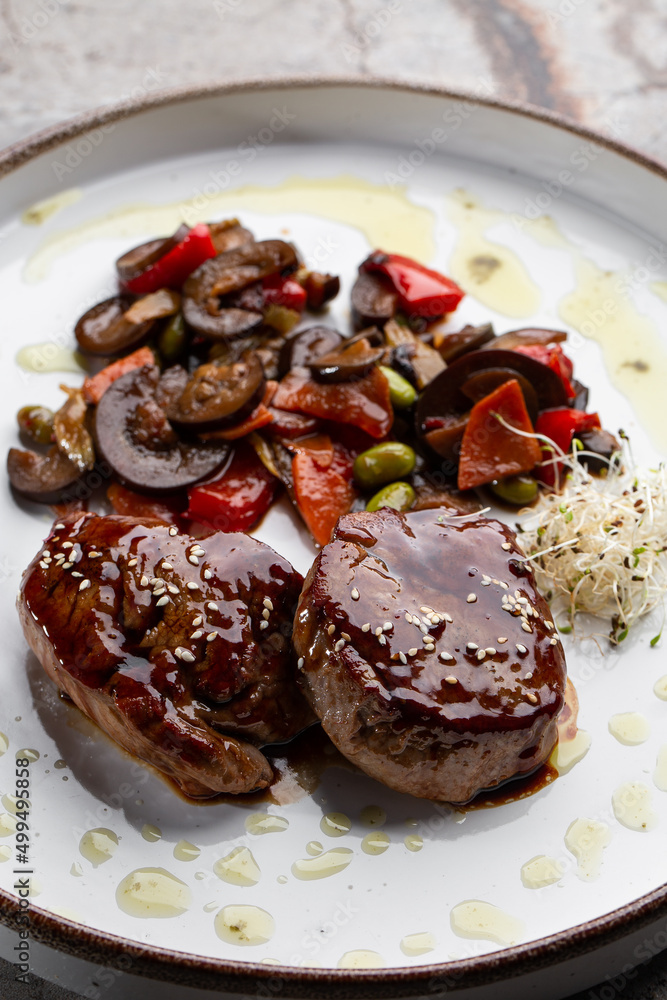 Grilled meat fillet steak wrapped in bacon medallions with raspberry sauce, served with vegetables and mushrooms