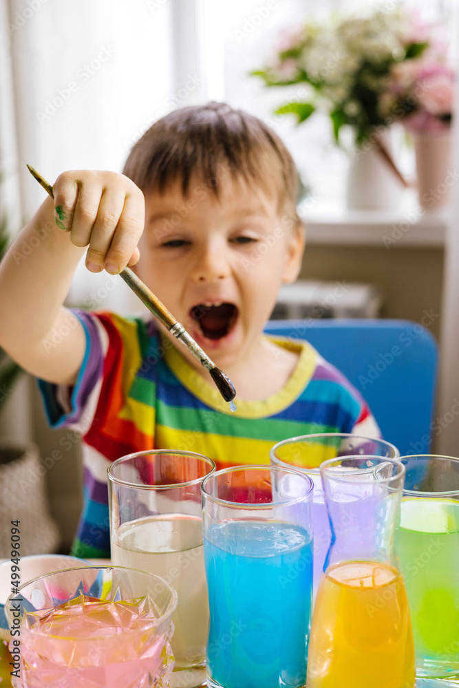 Cute baby boy learning mixing different colors with water and paint in containers. Early development Cute baby boy learning mixing different colors with water and paint in containers. Early development