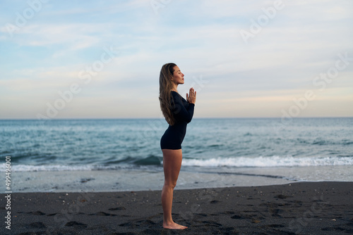 Fototapeta Naklejka Na Ścianę i Meble -  woman doing a yoga practice at the beach while a beautiful sunset