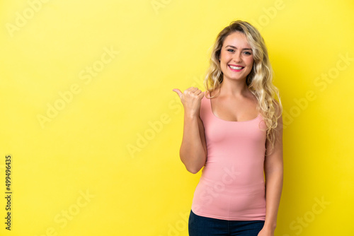 Young Brazilian woman isolated on yellow background pointing to the side to present a product