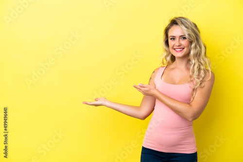 Young Brazilian woman isolated on yellow background extending hands to the side for inviting to come