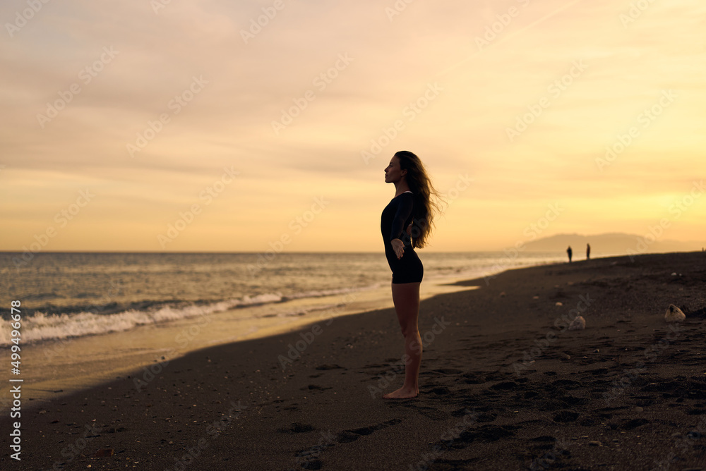 woman doing a yoga practice at the beach while a beautiful sunset woman doing a yoga practice at the beach while a beautiful sunset