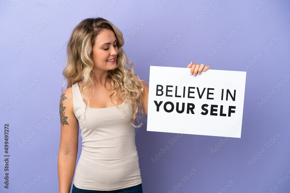 Young Brazilian woman isolated on purple background holding a placard with text Believe In Your Self Young Brazilian woman isolated on purple background holding a placard with text Believe In Your Self