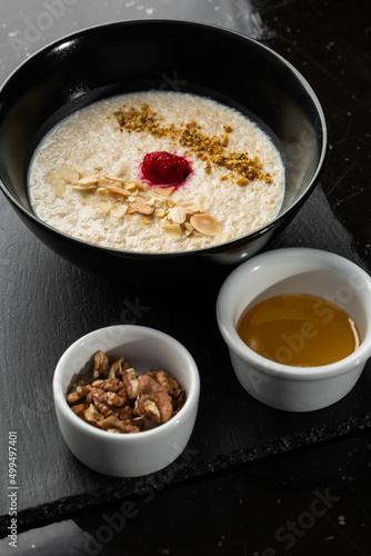 Wallpaper Mural Semolina porridge for breakfast oat with nuts in black bowl served with honey isolated on black stone background. Homemade food. Tasty breakfast. Selective focus. Torontodigital.ca