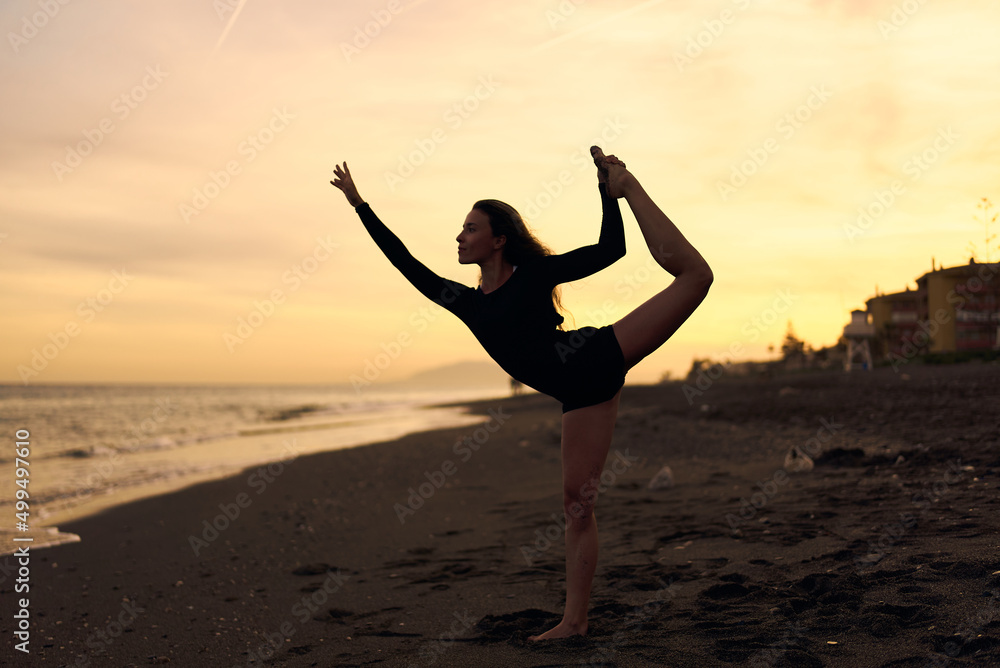 woman doing a yoga practice at the beach while a beautiful sunset woman doing a yoga practice at the beach while a beautiful sunset
